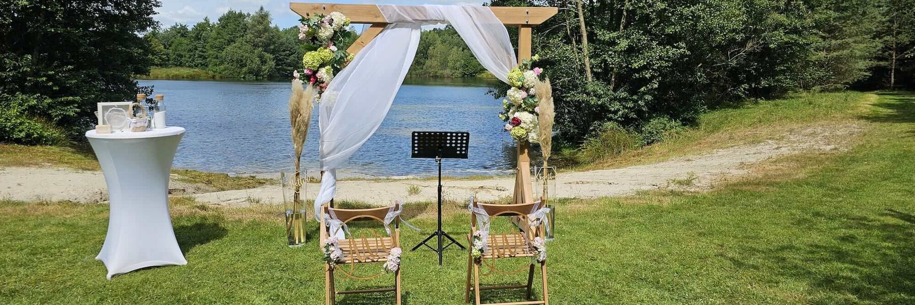 Zwei Stühle an einem See mit einem Torbogen und einem Stehtisch